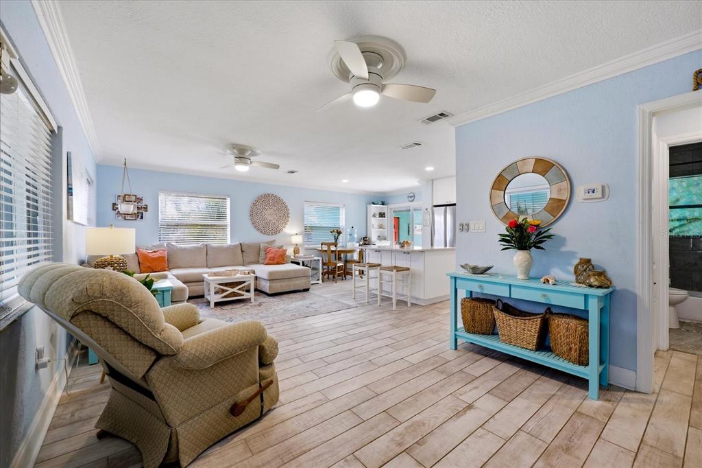 An open-concept living room and kitchen featuring light blue walls and wood-look tile flooring — 712 S GLENWOOD AVENUE, CLEARWATER, FL
