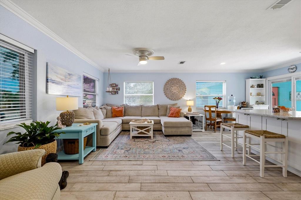 A living room with a sectional sofa, area rug, and an open kitchen with stools — 712 S GLENWOOD AVENUE, CLEARWATER, FL