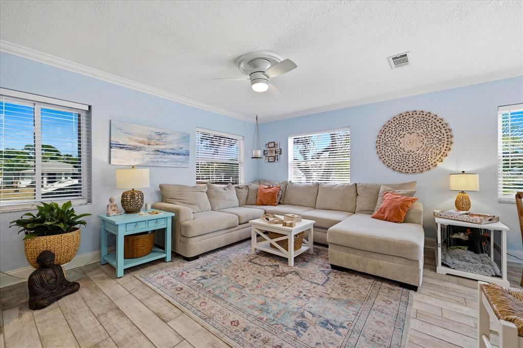 A light blue living room features a beige sectional sofa, area rug, and white furniture — 712 S GLENWOOD AVENUE, CLEARWATER, FL