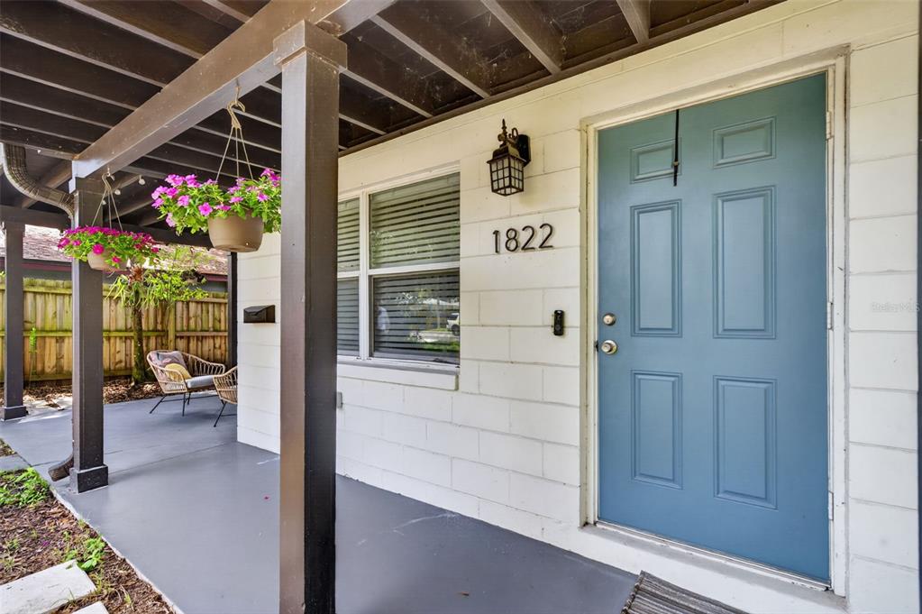 A covered porch features a blue front door, a hanging plant, and a patio chair — 1822 CANTON STREET, ORLANDO, FL