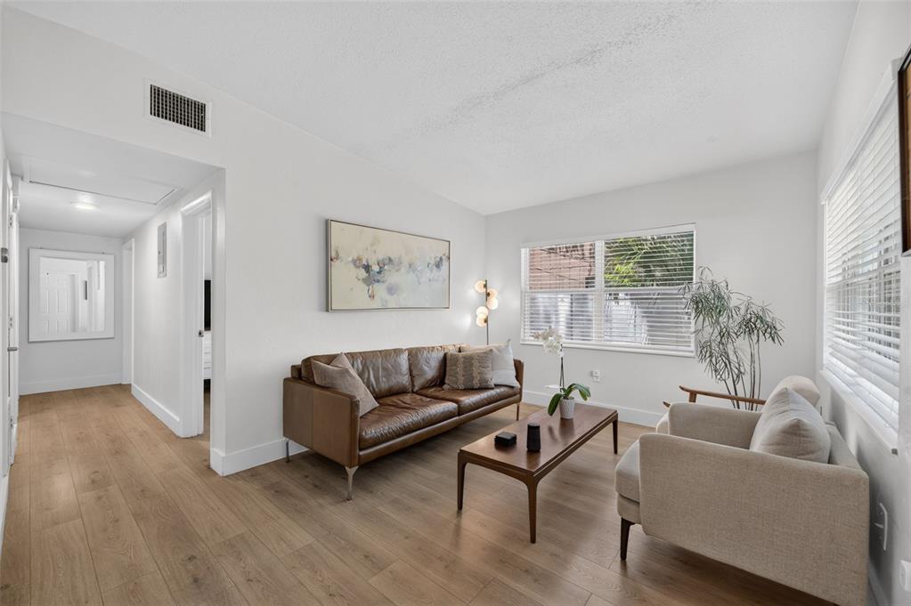 A living room features a brown leather sofa, a beige armchair, and light wood flooring — 1822 CANTON STREET, ORLANDO, FL