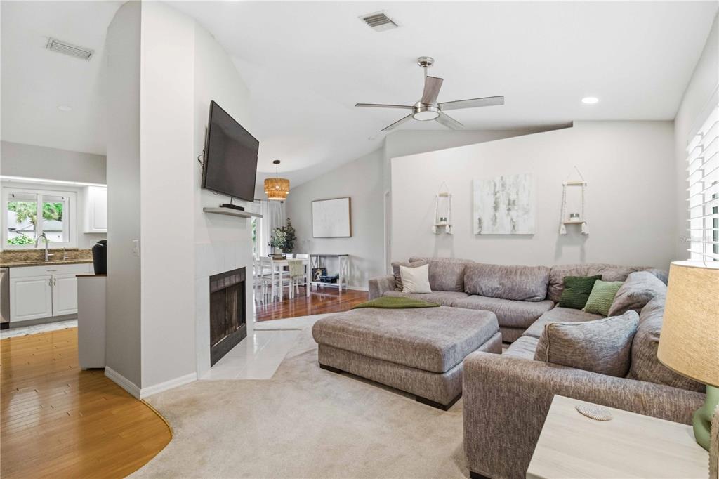 A living room with a fireplace, gray sectional sofa, and an adjacent kitchen — 3131 ARROWHEAD ROAD, VENICE, FL