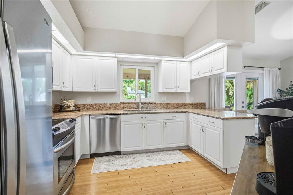 A kitchen with white cabinets, granite countertops, stainless steel appliances, and light wood flooring — 3131 ARROWHEAD ROAD, VENICE, FL