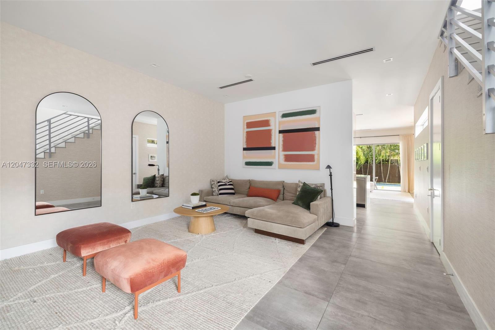 A modern living room features a beige sectional sofa, two pink ottomans, and arched mirrors — 3139 Ohio St # 3139, Coconut Grove FL 33133, COCONUT GROVE, FL