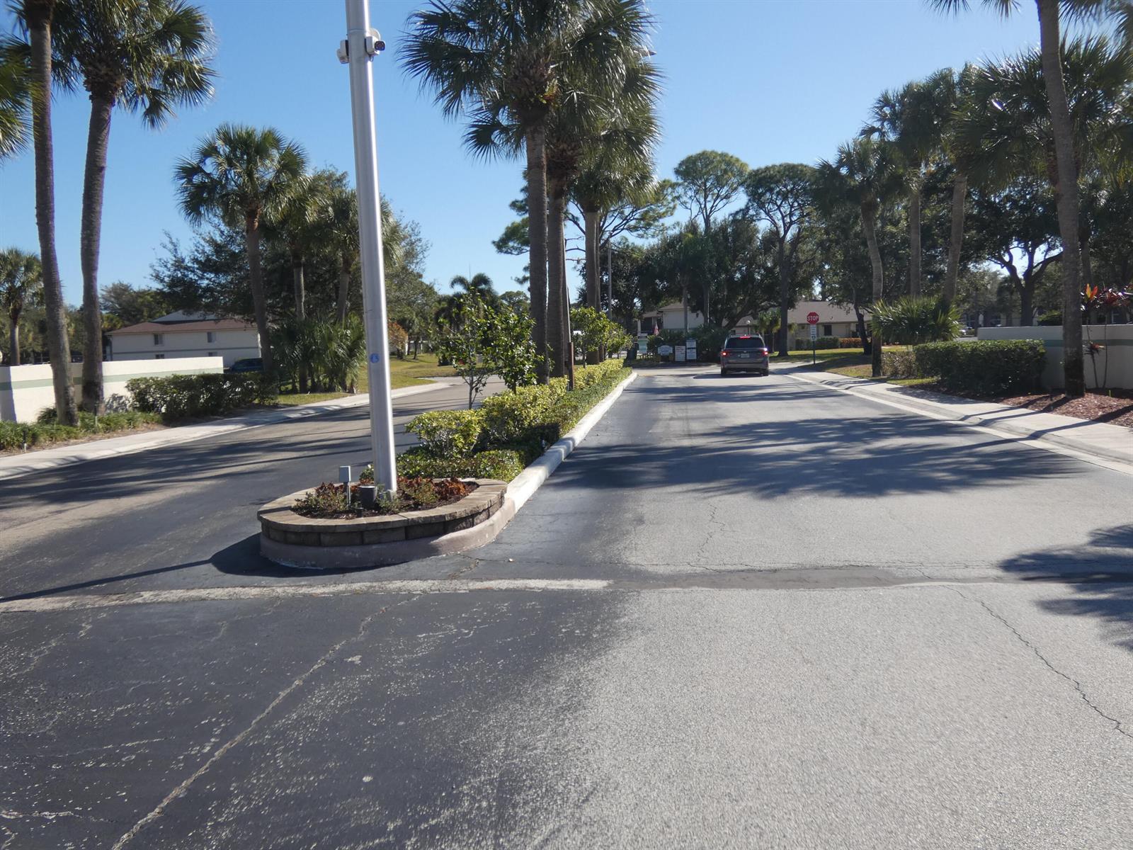 A paved road leads through a residential area lined with palm trees and landscaping — 6495 SE Chasewood Drive, Jupiter FL 33458, JUPITER, FL