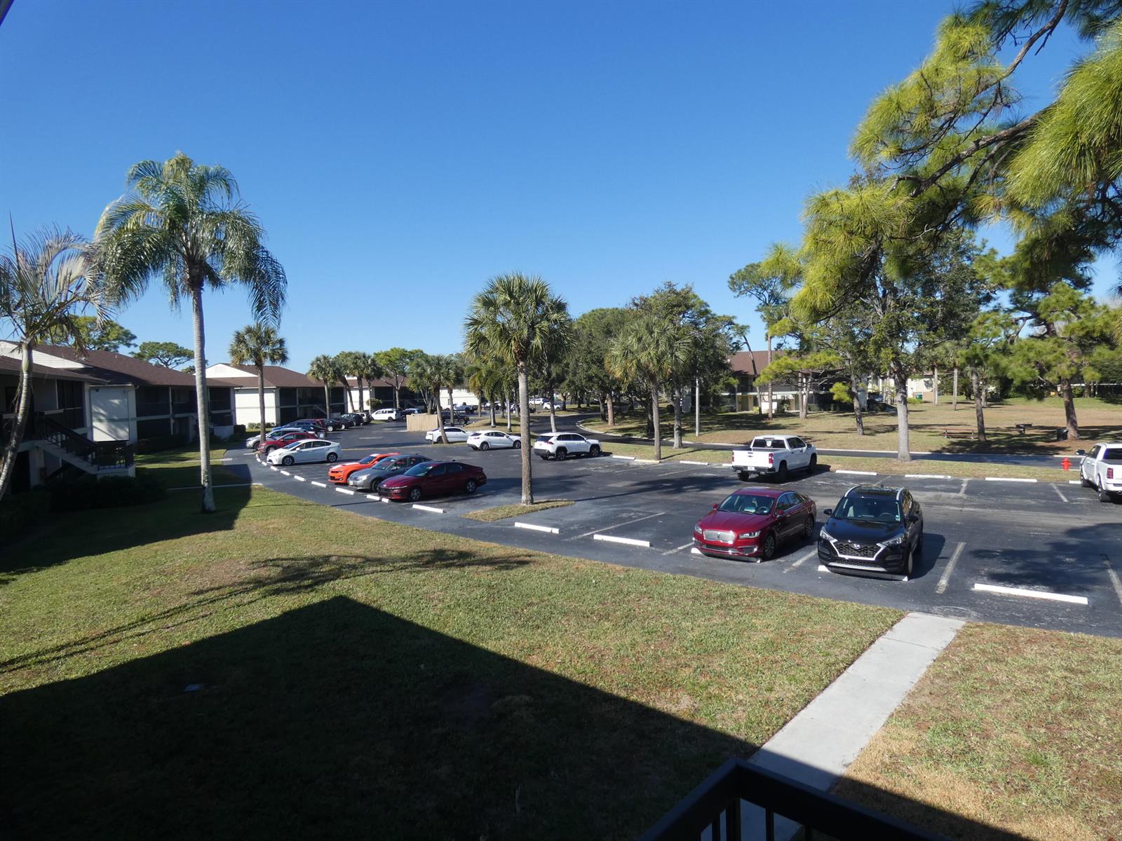 An outdoor parking lot with several parked cars surrounded by palm trees and apartment buildings — 6495 SE Chasewood Drive, Jupiter FL 33458, JUPITER, FL