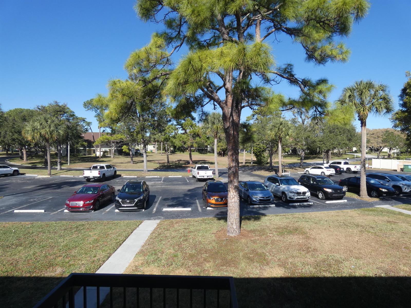 An elevated view of a parking lot with several cars parked under large pine trees — 6495 SE Chasewood Drive, Jupiter FL 33458, JUPITER, FL