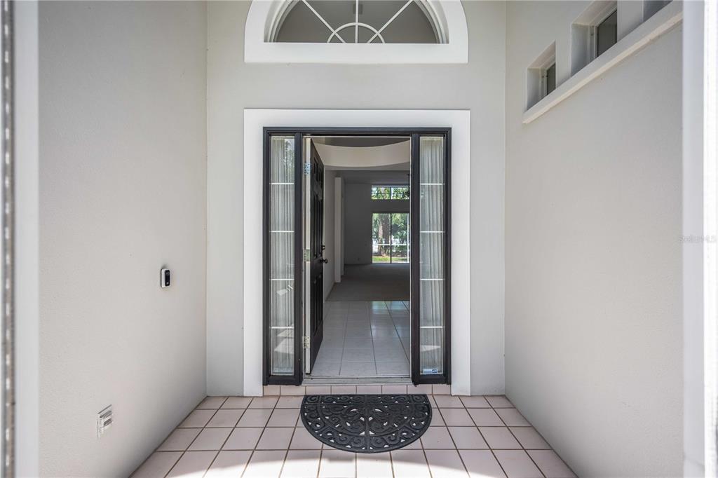 A front entryway features a tiled porch, a glass-paneled door, and a view inside — 7159 PRESTWICK COURT, UNIVERSITY PARK, FL