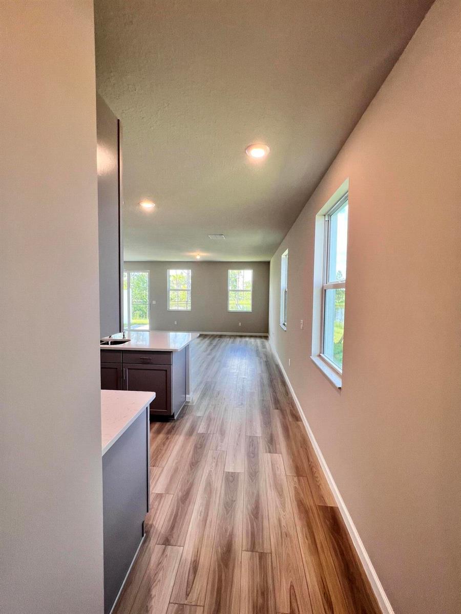 A view from a kitchen looking down a hallway toward a living area with windows — 240 Osprey Preserve Boulevard, Jensen Beach FL 34957, JENSEN BEACH, FL