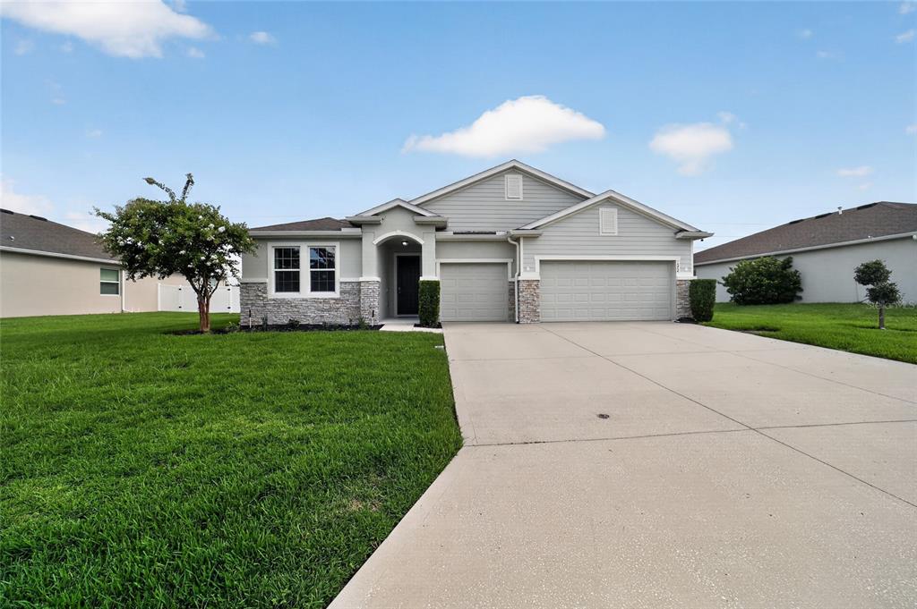 A single-story house with light gray siding, a stone facade, and a three-car garage — 4572 SW 65TH PLACE, OCALA, FL