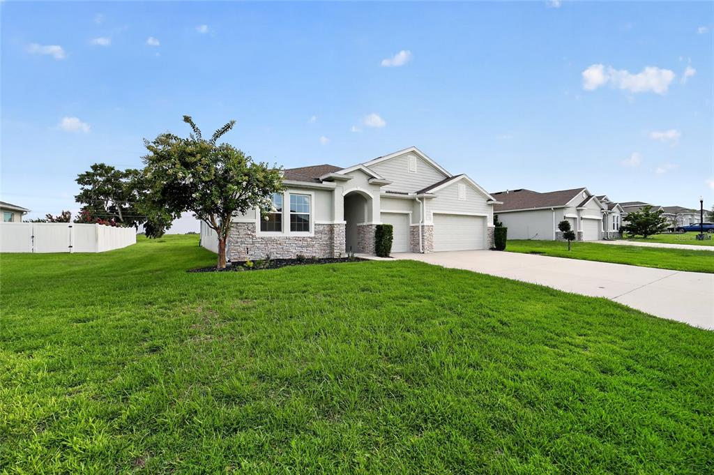 A single-story house with light siding, stone accents, and a two-car garage — 4572 SW 65TH PLACE, OCALA, FL