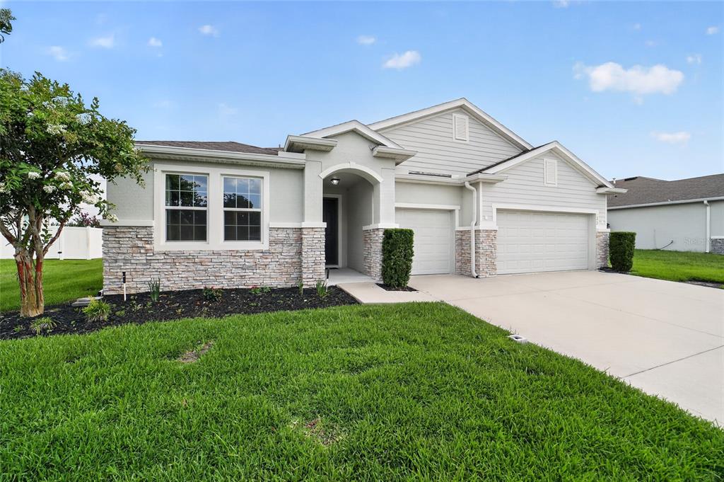 A single-story suburban house with a stone facade, two-car garage, and a manicured lawn — 4572 SW 65TH PLACE, OCALA, FL