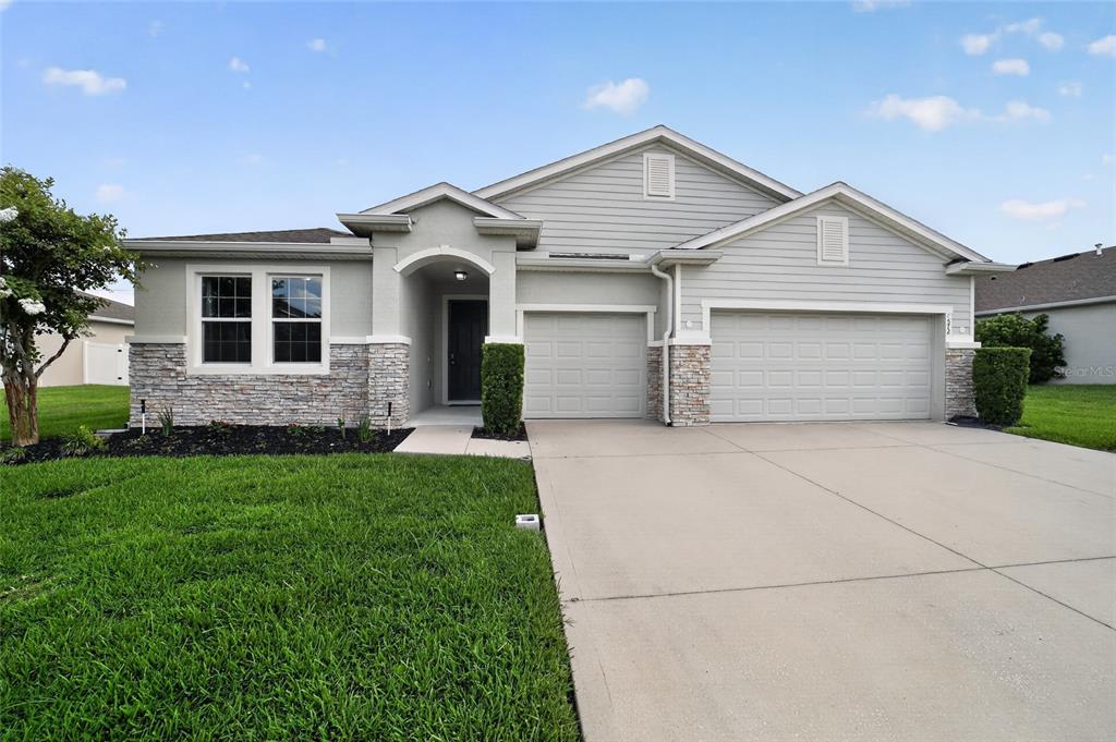 A single-story house with a stone facade, gray siding, and a three-car garage — 4572 SW 65TH PLACE, OCALA, FL