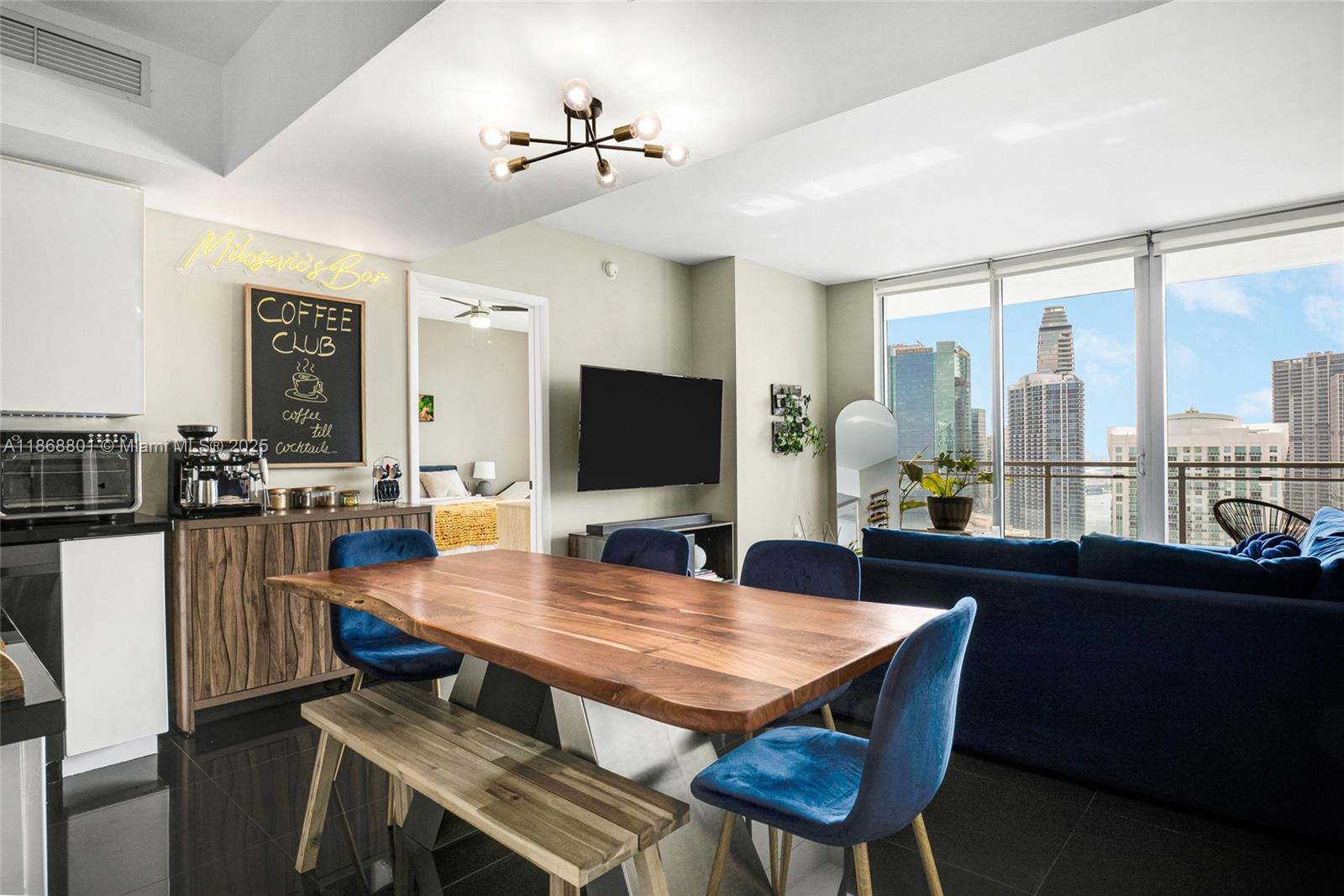 A dining area with a live-edge wooden table and blue chairs overlooks a city skyline — 92 SW 3rd St # 4312, Miami FL 33130, MIAMI, FL