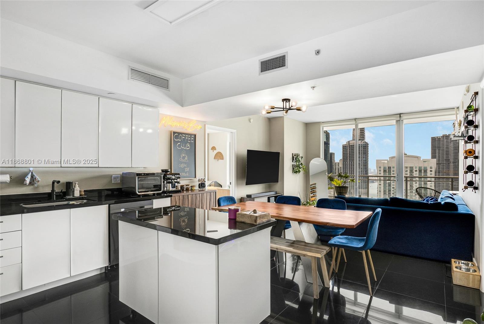 A modern kitchen and dining area features white cabinetry, black countertops, and a city view — 92 SW 3rd St # 4312, Miami FL 33130, MIAMI, FL