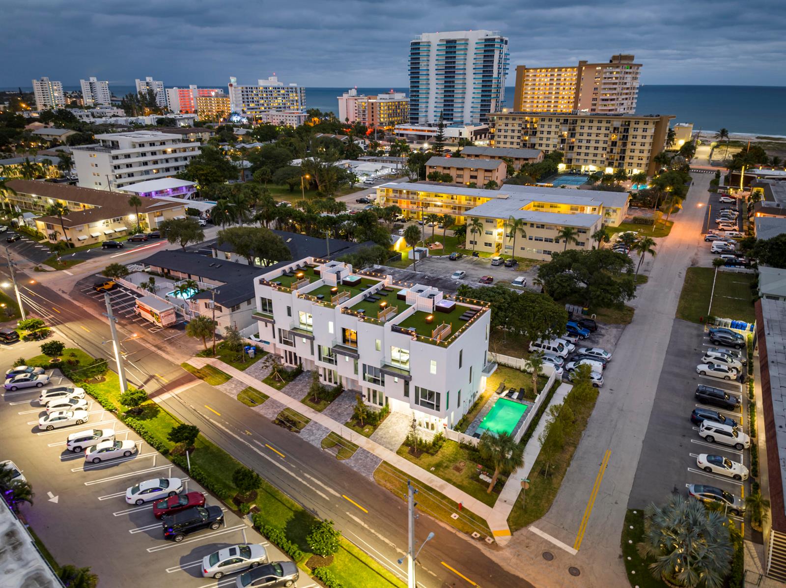 An aerial view of a modern white townhouse complex with rooftop decks and a pool — 1002 N Riverside Drive, Pompano Beach FL 33062, POMPANO BEACH, FL