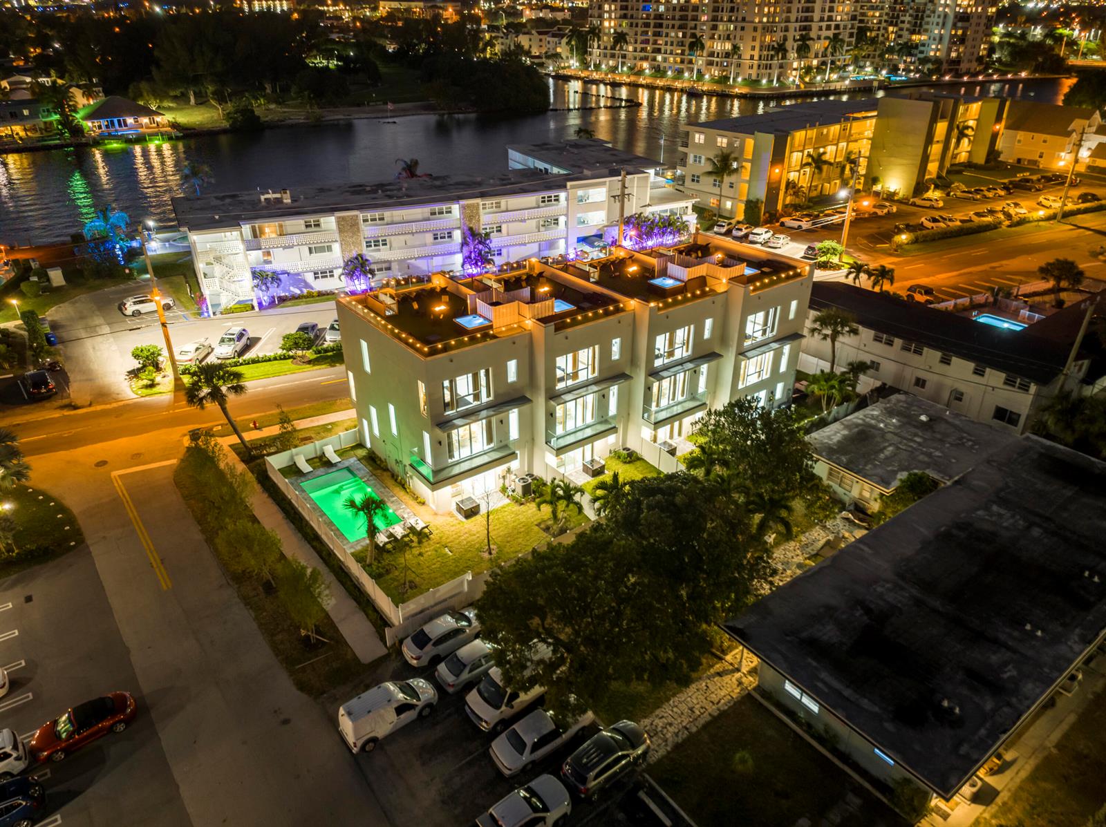 An aerial night view shows a modern multi-unit residential building with a pool and parking — 1002 N Riverside Drive, Pompano Beach FL 33062, POMPANO BEACH, FL