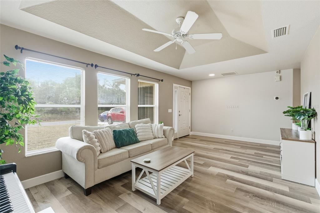 A living room features a vaulted ceiling, a white sofa, a coffee table, and wood-look flooring — 4409 KENOSKA STREET, NORTH PORT, FL