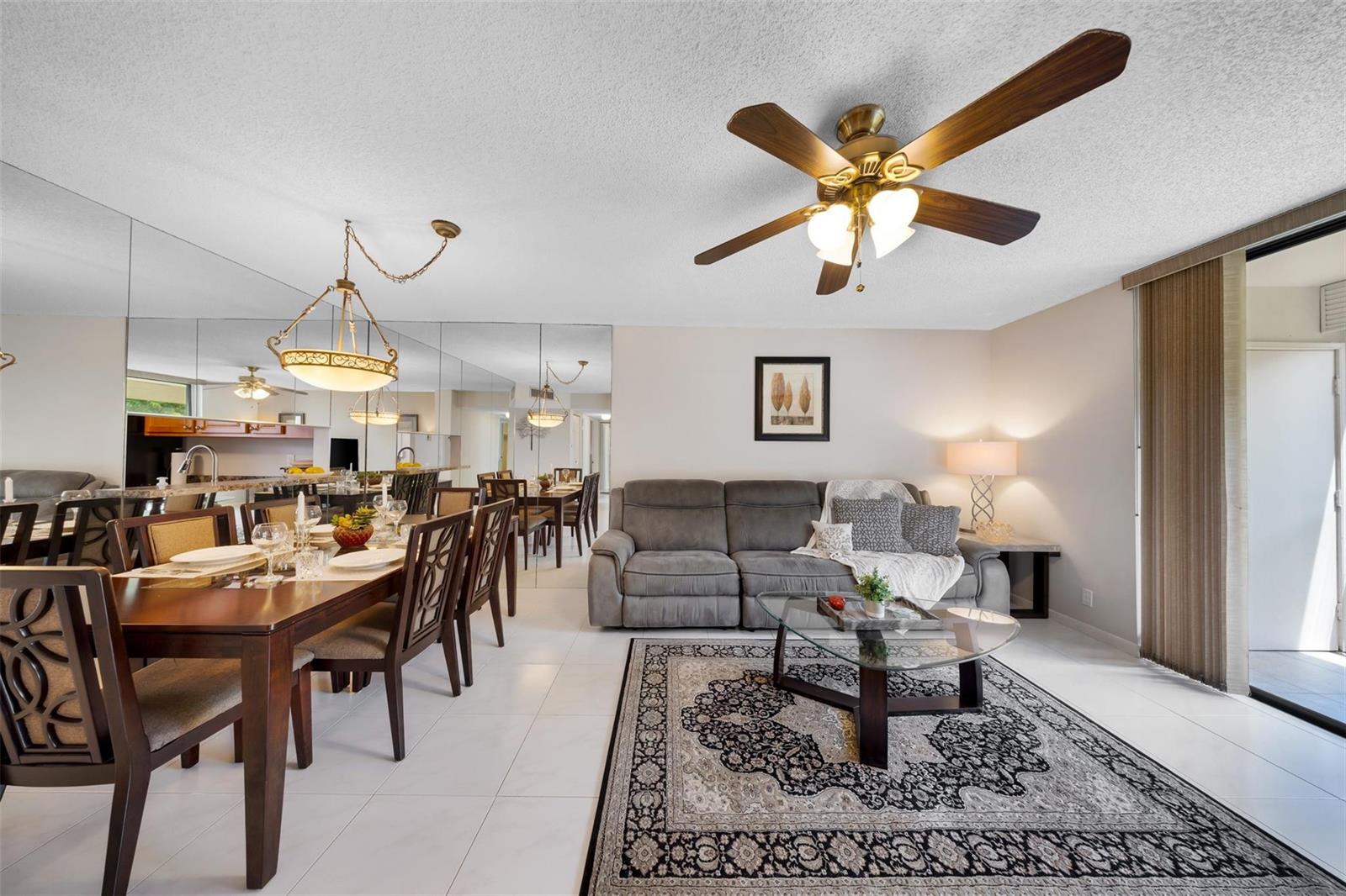 A living and dining room with tiled floors, a ceiling fan, and a mirrored wall — 5250 Las Verdes Circle # 317, Delray Beach FL 33484, DELRAY BEACH, FL