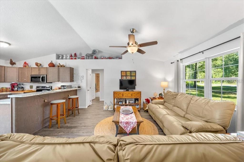 An open-concept living room features a kitchen with bar seating, wood flooring, and a ceiling fan — 543 N ROOKS AVENUE, INVERNESS, FL