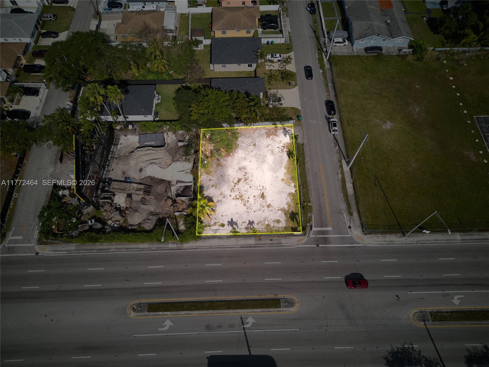 An aerial view shows a vacant, rectangular lot outlined in yellow next to a construction site — 1405 NW 79th St, Miami FL 33147, MIAMI, FL