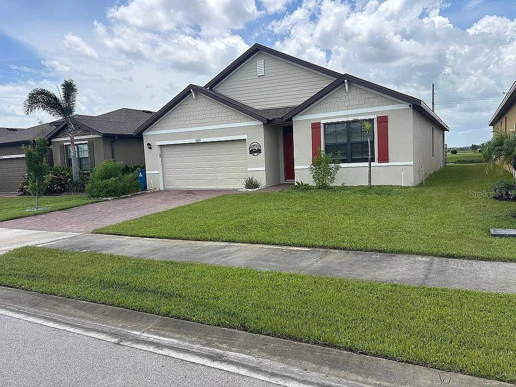 A single-story suburban house with a beige exterior, red shutters, and a two-car garage — 3720 FOGGY MIST ROAD SE, PALM BAY, FL