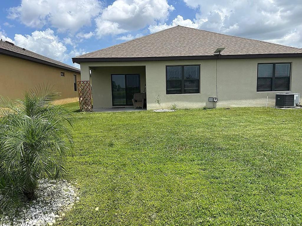 The exterior rear view of a single-story house features a patio, lawn, and palm tree — 3720 FOGGY MIST ROAD SE, PALM BAY, FL