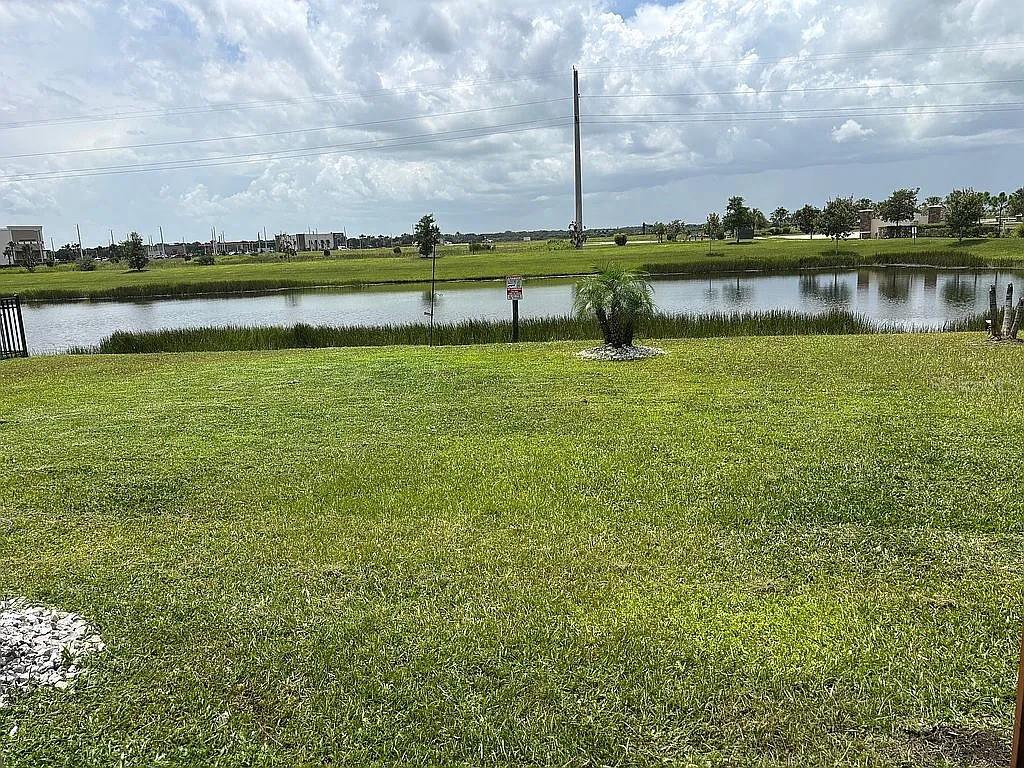 A grassy lawn leads to a retention pond under a cloudy sky — 3720 FOGGY MIST ROAD SE, PALM BAY, FL