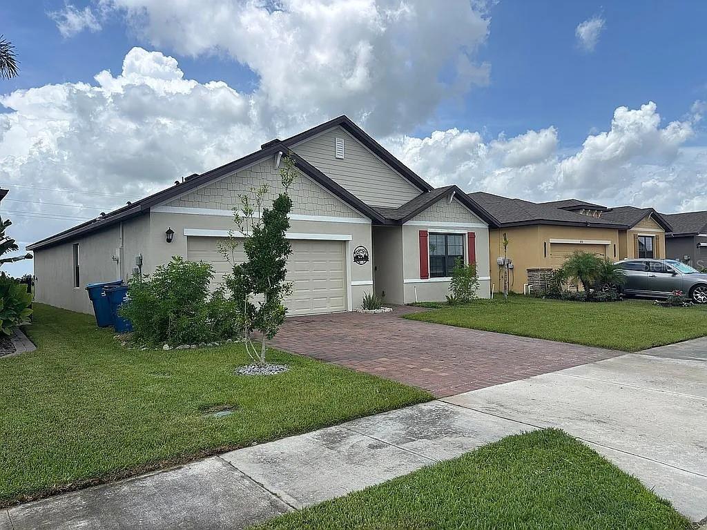 A single-story house with a beige stucco exterior, a brick driveway, and a two-car garage — 3720 FOGGY MIST ROAD SE, PALM BAY, FL