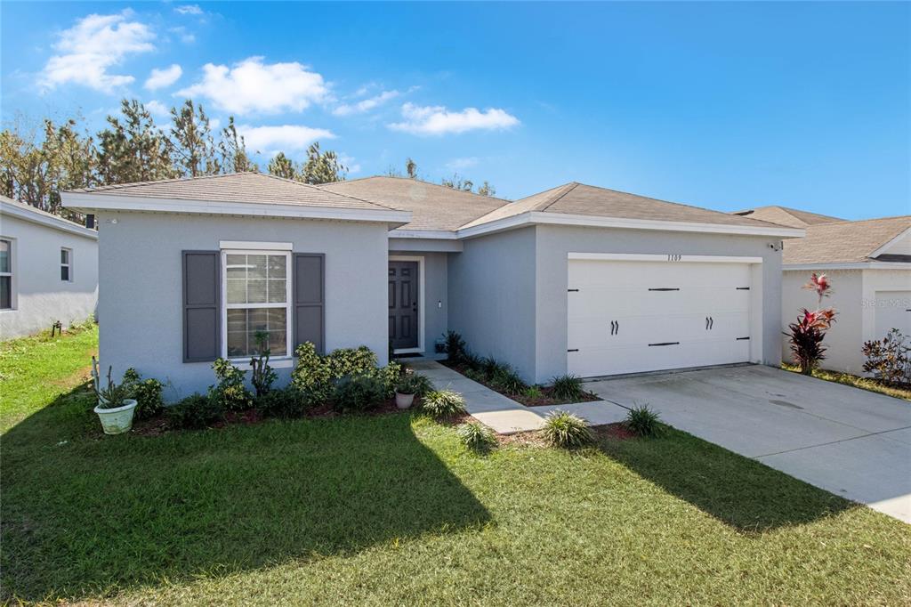 A single-story house with a gray exterior, a two-car garage, and a front lawn — 1109 CATSKILL DRIVE, HAINES CITY, FL