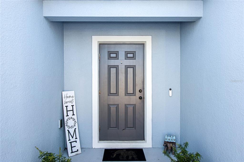 A gray front door with a white frame is centered on a light blue exterior wall — 1109 CATSKILL DRIVE, HAINES CITY, FL