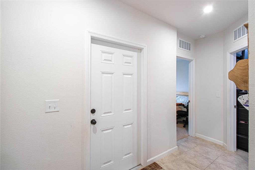 A white interior door stands next to a hallway leading to a bedroom with tile flooring — 1109 CATSKILL DRIVE, HAINES CITY, FL