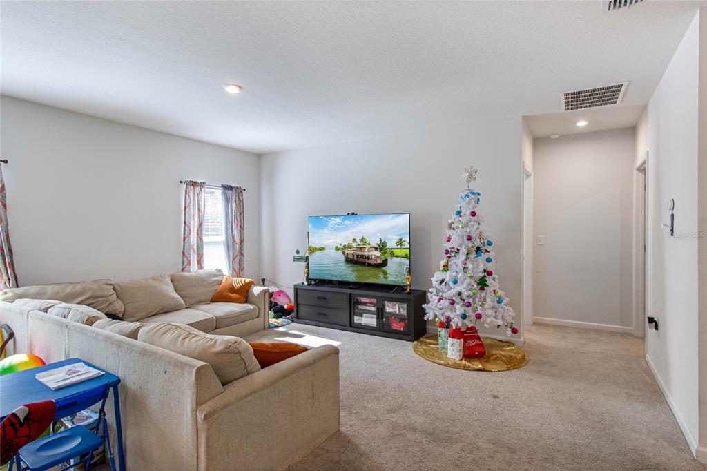 A living room features a beige sectional sofa, a television on a stand, and a Christmas tree — 1109 CATSKILL DRIVE, HAINES CITY, FL