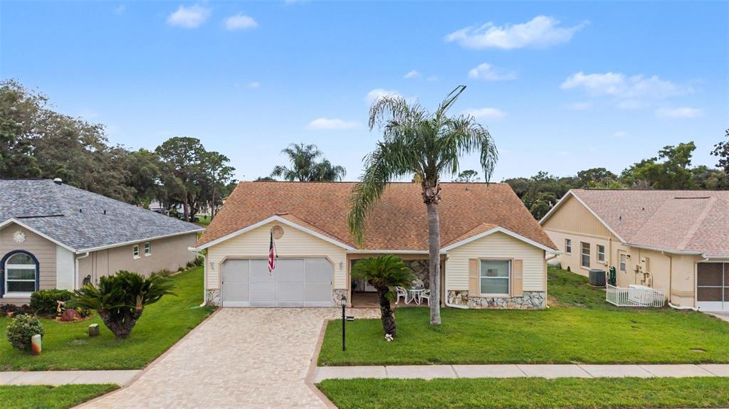 A single-story house with a paved driveway, a palm tree, and a two-car garage — 4709 PORTLAND MANOR DRIVE, NEW PORT RICHEY, FL