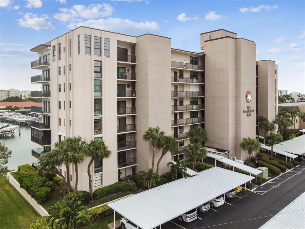 An exterior view of a multi-story apartment building with a covered parking area and marina — 7600 SUN ISLAND DRIVE S UNIT 204, SOUTH PASADENA, FL