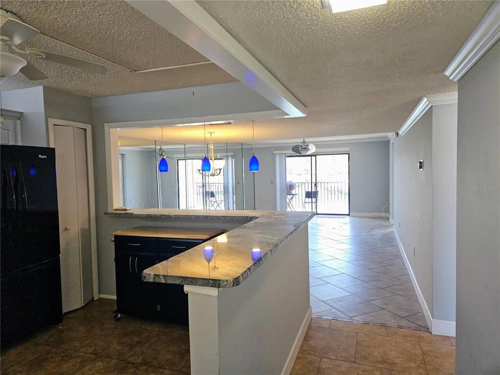 A kitchen with a granite breakfast bar overlooks a living area with sliding glass doors — 7600 SUN ISLAND DRIVE S UNIT 204, SOUTH PASADENA, FL