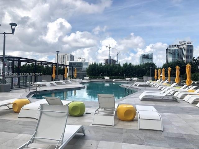 A rooftop swimming pool area features lounge chairs, yellow side tables, and umbrellas — MIAMI, FL