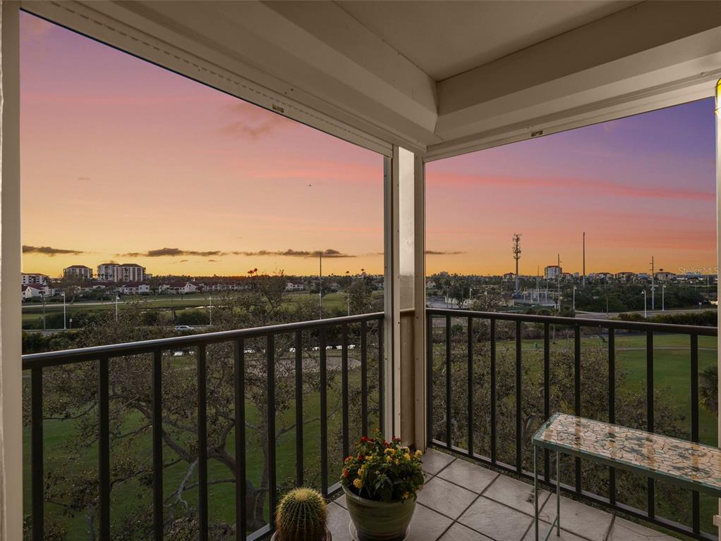 A balcony with a metal railing overlooks a golf course at sunset — 6269 PALMA DEL MAR BOULEVARD S UNIT 608, ST PETERSBURG, FL
