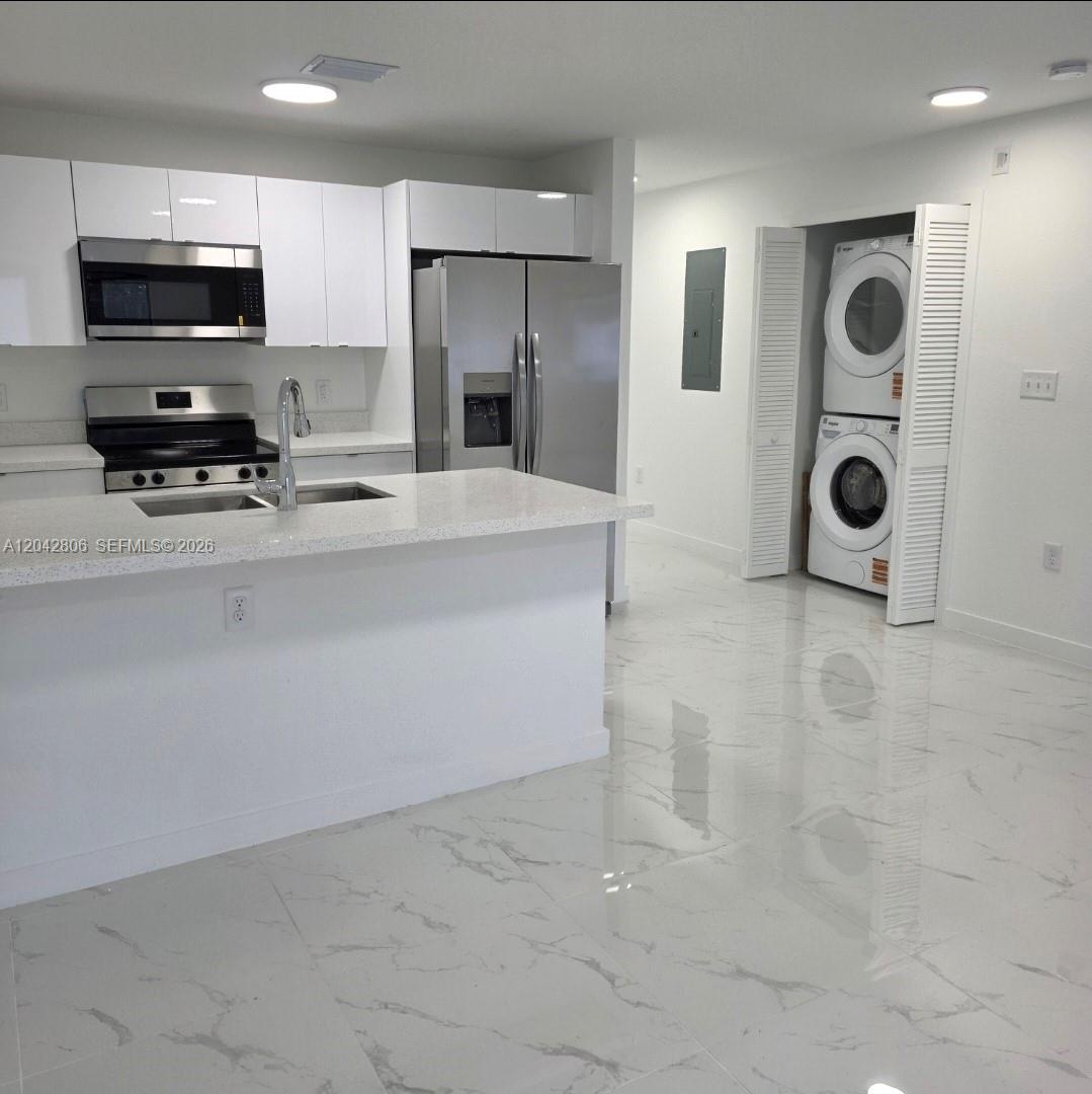 A modern kitchen features white cabinets, stainless steel appliances, a quartz island, and tiled floors — 2729 NW 44 St # 2729, Miami FL 33142, MIAMI, FL