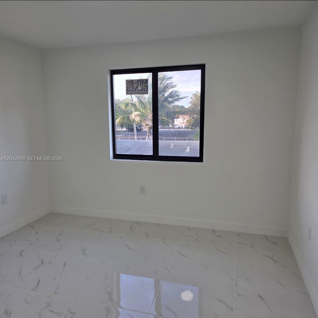 An empty room features white walls, marble-patterned tile flooring, and a single black-framed window — 2729 NW 44 St # 2729, Miami FL 33142, MIAMI, FL