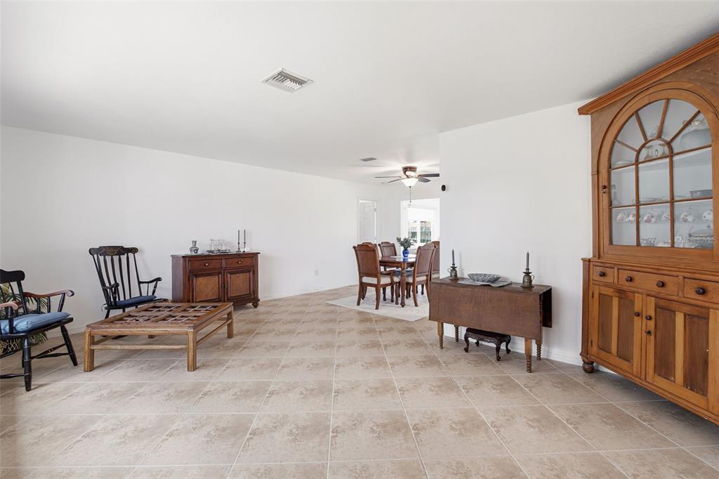 A living and dining area with tile flooring, white walls, and traditional wooden furniture — 235 TAIT TERRACE SE, PORT CHARLOTTE, FL