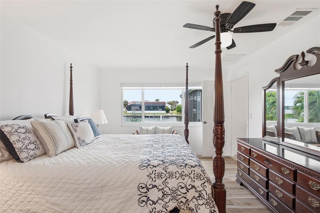 A bedroom features a four-poster bed, a wooden dresser, and a view of a canal — 235 TAIT TERRACE SE, PORT CHARLOTTE, FL