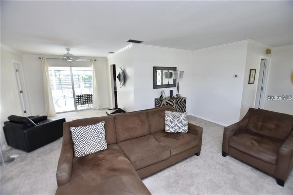A living room features a brown sectional sofa, an armchair, and a sliding glass door — 3926 CALLIANDRA DRIVE, SARASOTA, FL