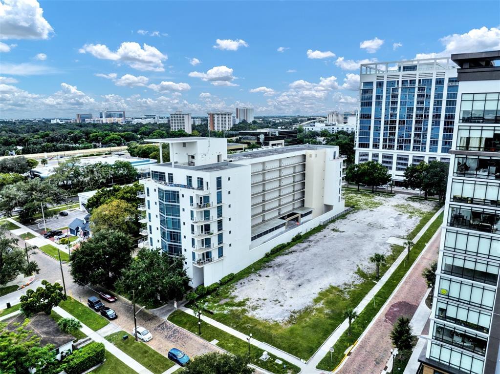 An aerial view shows a white mid-rise building next to a large vacant dirt lot — 525 E JACKSON STREET UNIT 402, ORLANDO, FL