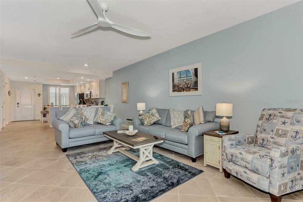 A living room features light blue sofas, a patterned armchair, and a central coffee table — 12440 WELLEN GOLF STREET UNIT 107, VENICE, FL