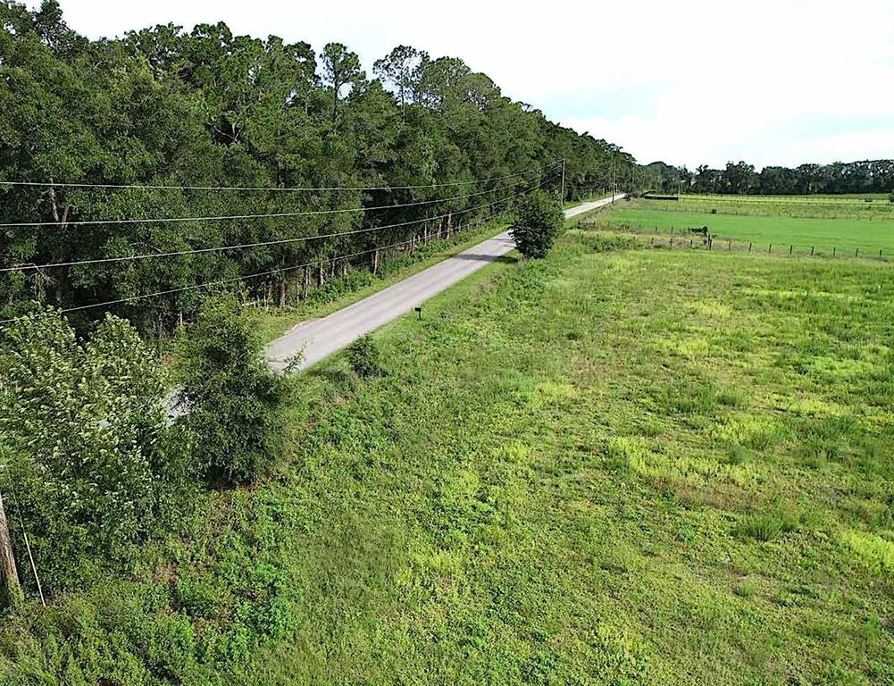 An aerial view shows a large, grassy, undeveloped plot of land bordering a dirt road — 00 SW 210 AVENUE, DUNNELLON, FL