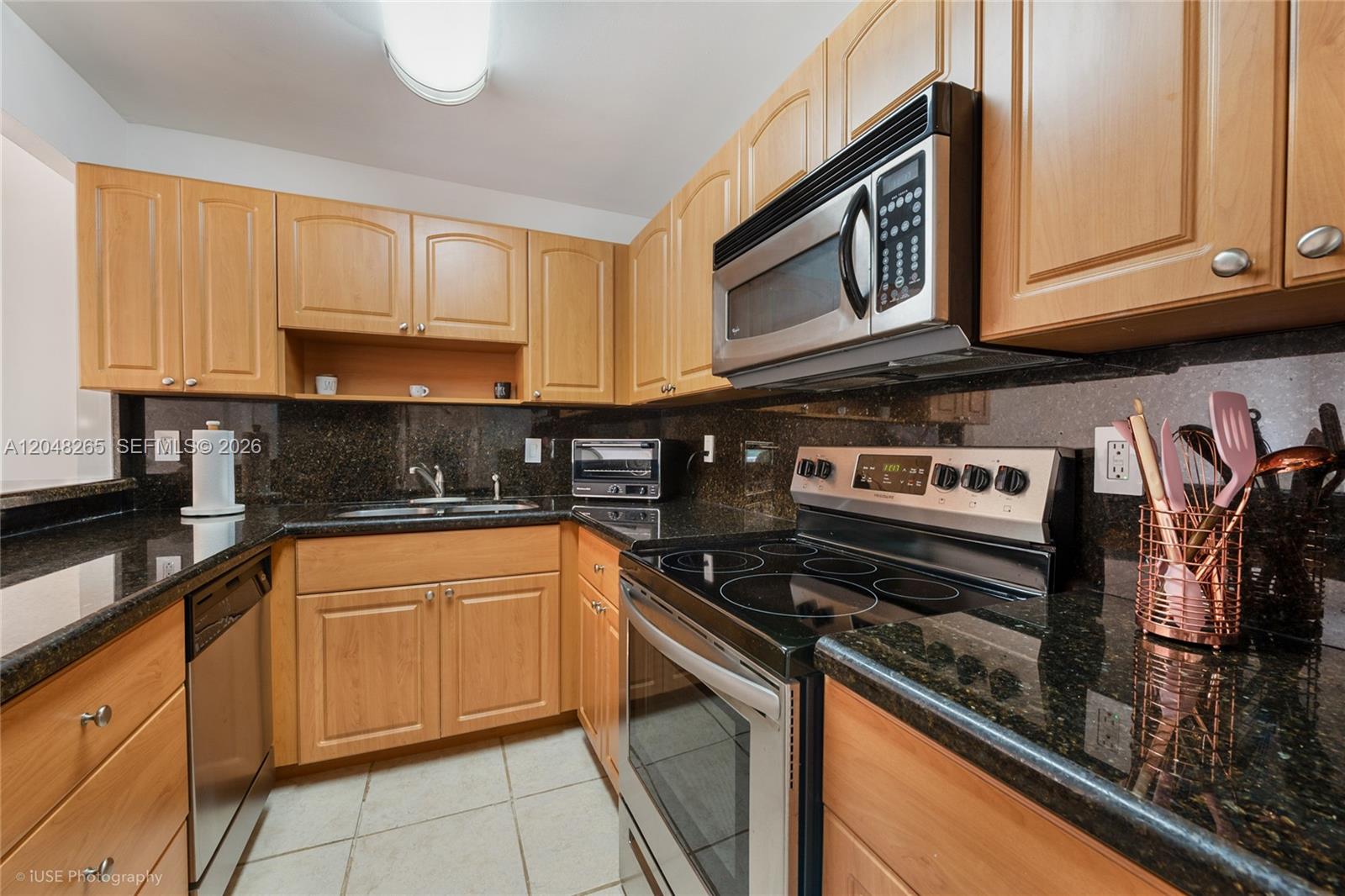 A kitchen features wood cabinets, dark granite countertops, stainless steel appliances, and tile flooring — 9301 SW 92nd Ave # A304, Miami FL 33176, MIAMI, FL