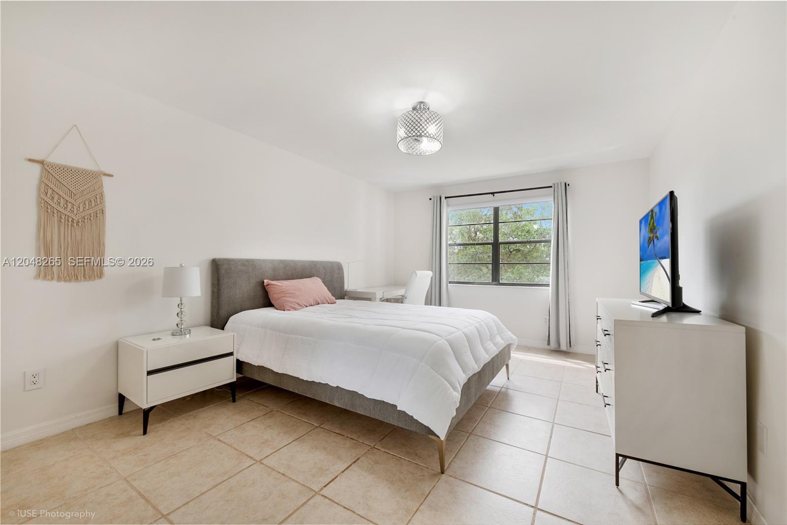A bedroom features a gray upholstered bed, white furniture, tile flooring, and a window — 9301 SW 92nd Ave # A304, Miami FL 33176, MIAMI, FL