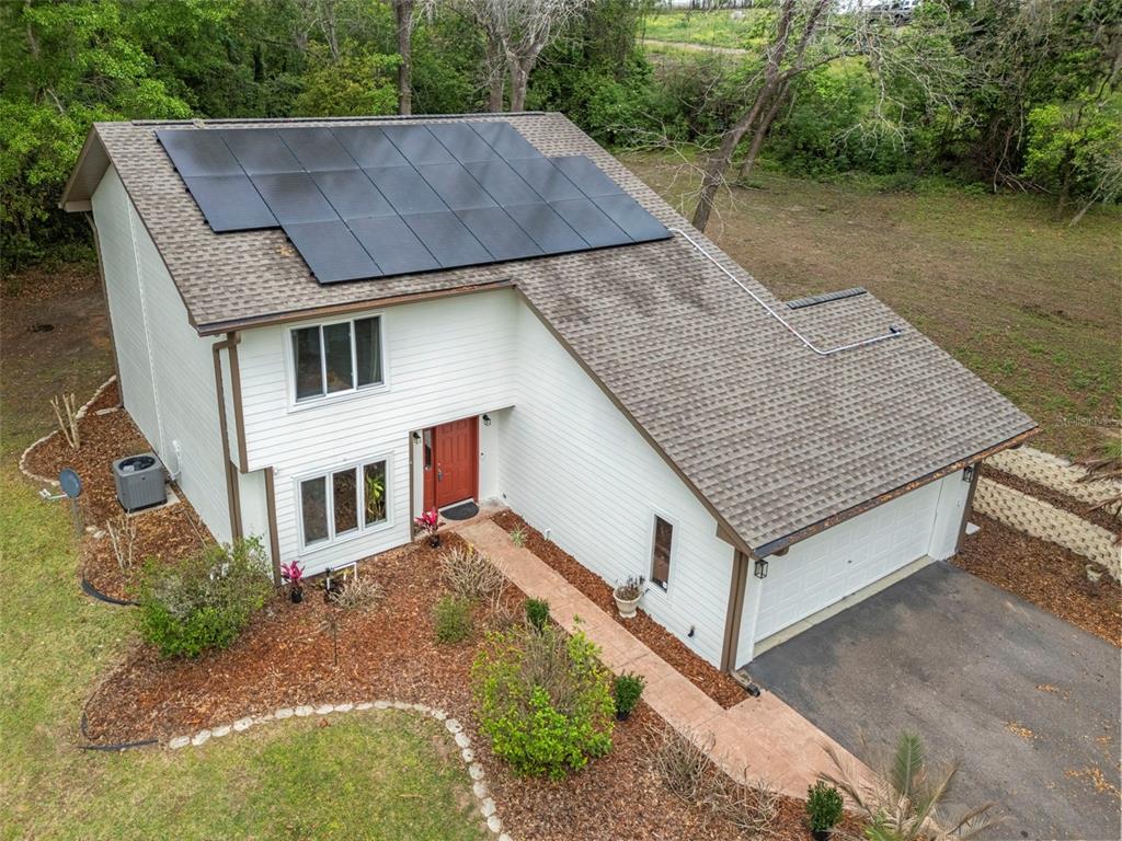An aerial view shows a two-story house with solar panels on the roof and a driveway — 15839 POWERLINE ROAD, DADE CITY, FL