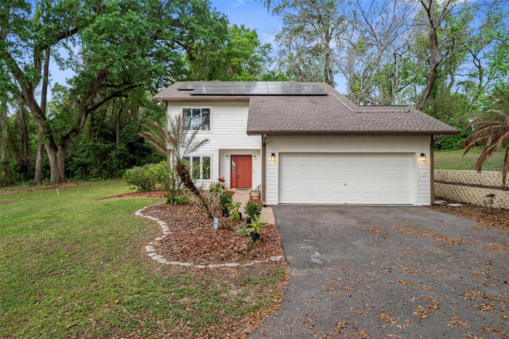 A two-story house with white siding, a red front door, and solar panels on the roof — 15839 POWERLINE ROAD, DADE CITY, FL